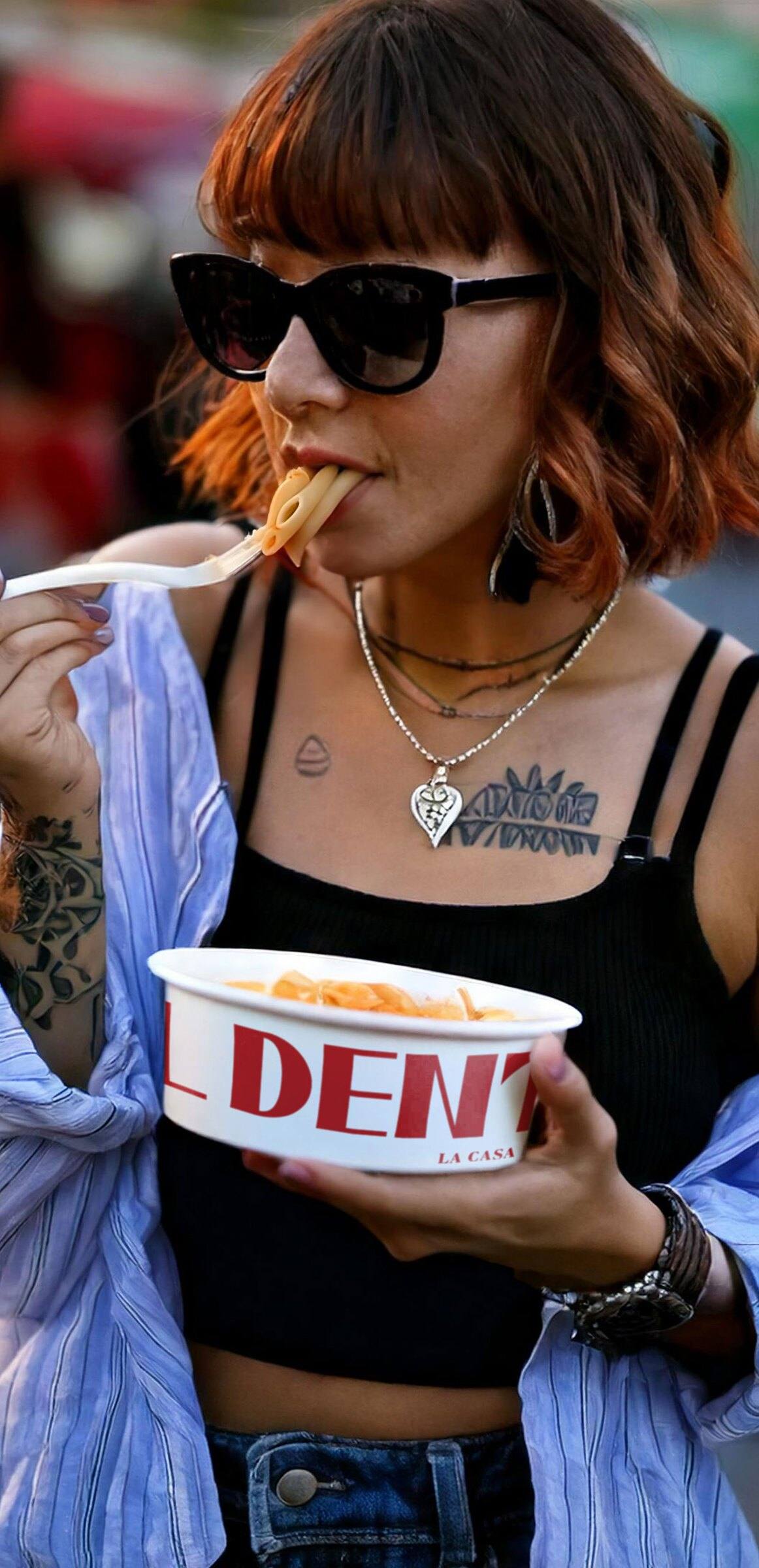 A guest eating pasta from an Al Dente bowl on the street