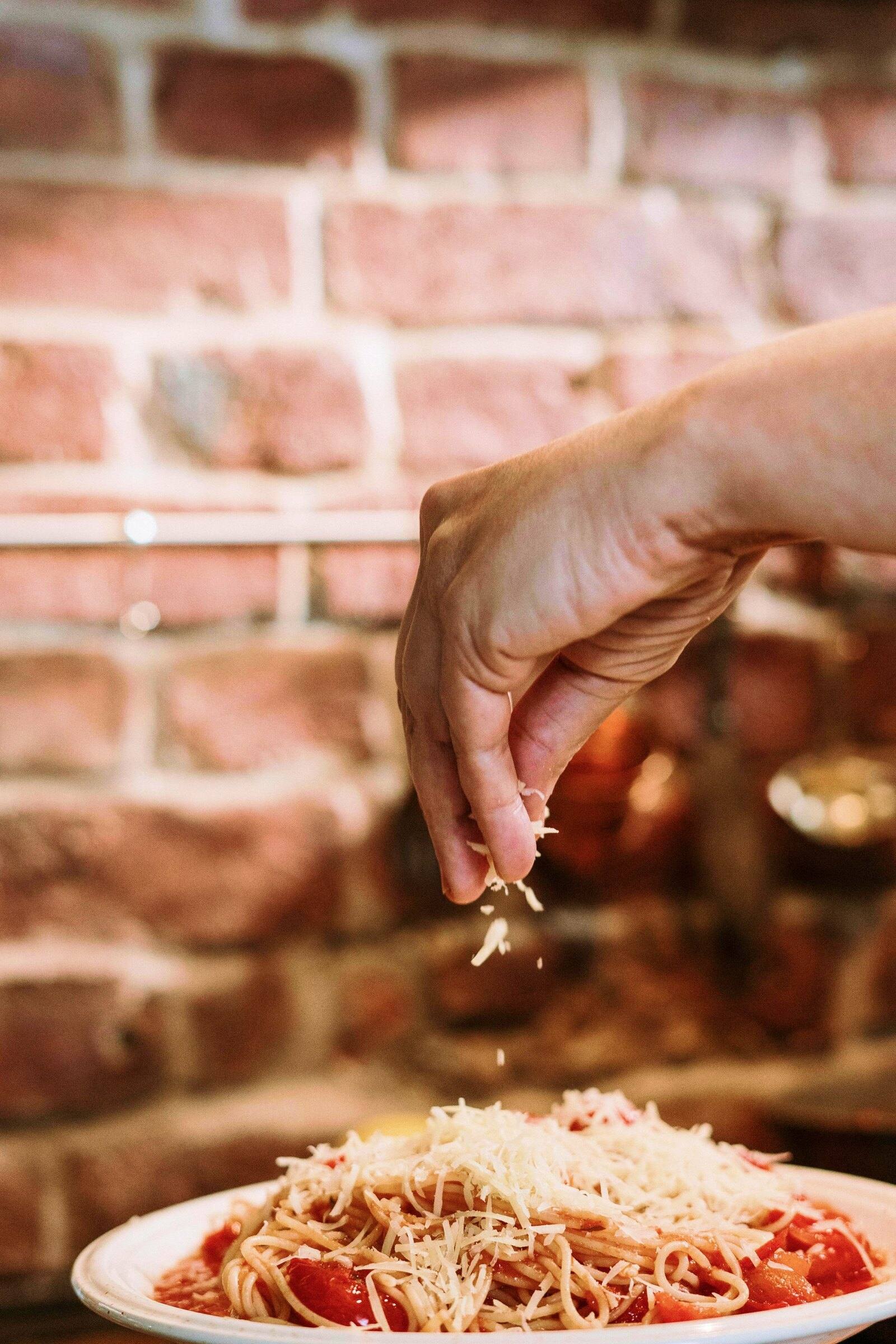 Parmesan falling onto a plate of spaghetti